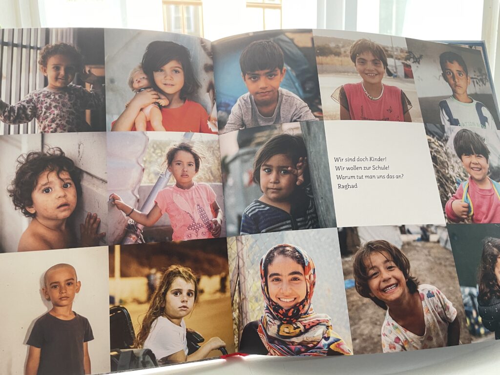 Eine Doppelseite des Buches mit zahlreichen Kinderportraits. In der Mitte steht ein Zitat von Raghad: "Wir sind doch Kinder! Wir wollen zur Schule. Warum tut man uns das an?"