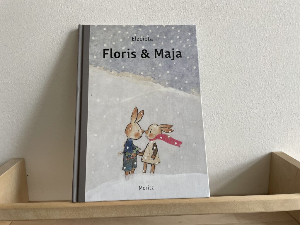Das Cover des Buches Floris & Maja. Zwei Hasenkinder stehen im Schnee und geben sich ein Nasenbussi. 
